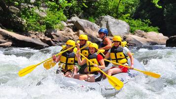 Een groep mensen in een raft die een rivier bevaart, omringd door rotsen en begroeiing.