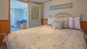Une chambre à coucher avec un grand lit, une tête de lit en bois et un panneau mural sur lequel on peut lire : « Embrasse-moi toujours avant de dormir ».