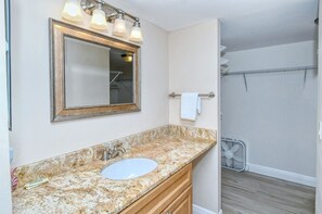 A bathroom with a granite countertop sink, a large mirror, and a towel rack. - Doveplum 220-2 level 2BR/2.5BA townhome has tropical views overlooking both pool and Gulf (Sarasota)