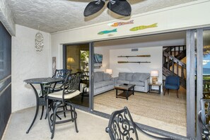 A living room with a sofa, coffee table, and chairs, a dining area with a table and chairs, and a staircase leading to an upper level.