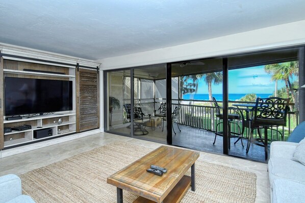 A modern living room with a large flat-screen TV, a wooden coffee table, and a sofa.
