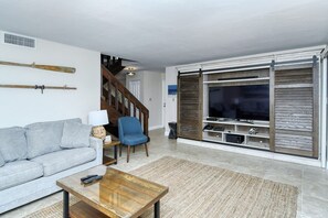A living room with a sofa, a coffee table, a TV, and a staircase.