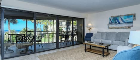 Ein Wohnzimmer mit Balkon, einer Couch, einem Couchtisch und einem Gemälde.