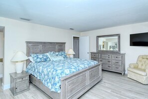 A bedroom with a bed, bedside tables, a dresser, a chair, and a TV.