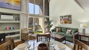 Un área de estar amplia con una mesa de comedor, sillas, un sofá y un ventilador de techo.