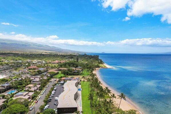 A coastal town with a beach, residential buildings, and a road leading to the beach.
