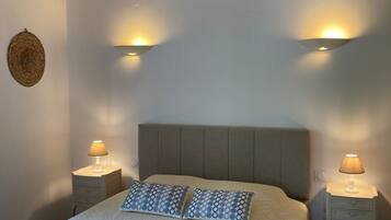 Een slaapkamer met een bed, twee nachtkastjes met lampen, een hoofdbord en een wandlamp.