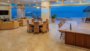 A spacious living area with a large dining table, comfortable seating, and a view of the ocean. - Villa Del Mar-5 Star Luxury Villa with Epic Views (Cabo San Lucas)