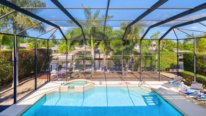 A pool area with a glass enclosure, lounge chairs, and a view of the surrounding landscape.