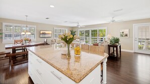 A spacious kitchen with a granite countertop, white cabinetry, and a dining area with a bench.