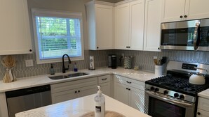 A modern kitchen with white cabinets, a stainless steel microwave, a gas stove, and a dishwasher. - Family Home Near LakePoint Sports with Fenced Yard (Acworth)
