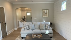 A living room with a grey sofa, patterned cushions, a dark coffee table, and a light-colored rug. - Family Home Near LakePoint Sports with Fenced Yard (Acworth)