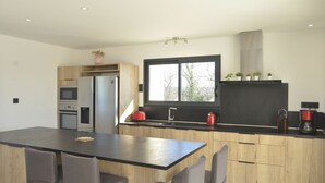 Une cuisine moderne dotée d’un îlot central, de meubles en bois et d’une grande fenêtre.