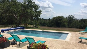Une piscine avec des chaises longues et des jardinières fleuries.
