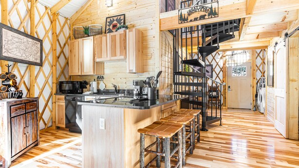 Une cuisine spacieuse dotée de meubles en bois, d’un îlot central et d’un escalier menant à une mezzanine.