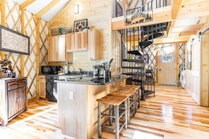 Une cuisine spacieuse dotée de meubles en bois, d’un îlot central et d’un escalier menant à une mezzanine.