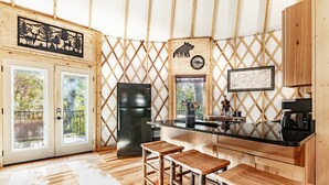 Une cuisine rustique avec des tabourets en bois, un réfrigérateur et un mur en bois orné de la silhouette d’un ours.