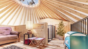 Un intérieur chaleureux avec un plafond en bois, un canapé, une petite table, un sapin de Noël et un réfrigérateur de style vintage.