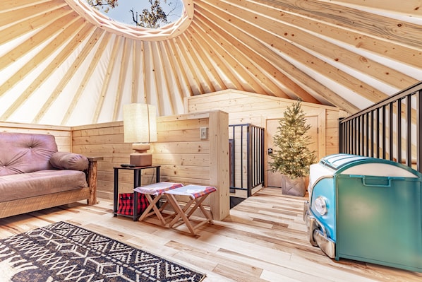 Un intérieur chaleureux avec un plafond en bois, un canapé, une petite table, un sapin de Noël et un réfrigérateur de style vintage.