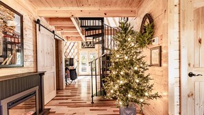 Un intérieur en bois avec un escalier, une cheminée et un sapin de Noël.