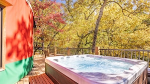 Un bain à remous sur une terrasse en bois, avec vue sur les arbres aux couleurs automnales.
