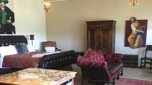 A spacious living room with a wooden cabinet, a sofa, a red patterned rug, and a painting on the wall. - Historic Schoolhouse Flat by Verde Canyon Railroad (Clarkdale)