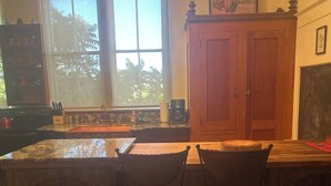 A kitchen with a large window, wooden cabinets, and a bar area with two chairs. - Historic Schoolhouse Flat by Verde Canyon Railroad (Clarkdale)