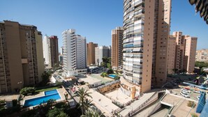 Een hoog appartementencomplex met meerdere balkons, een zwembad en een parkeerplaats.