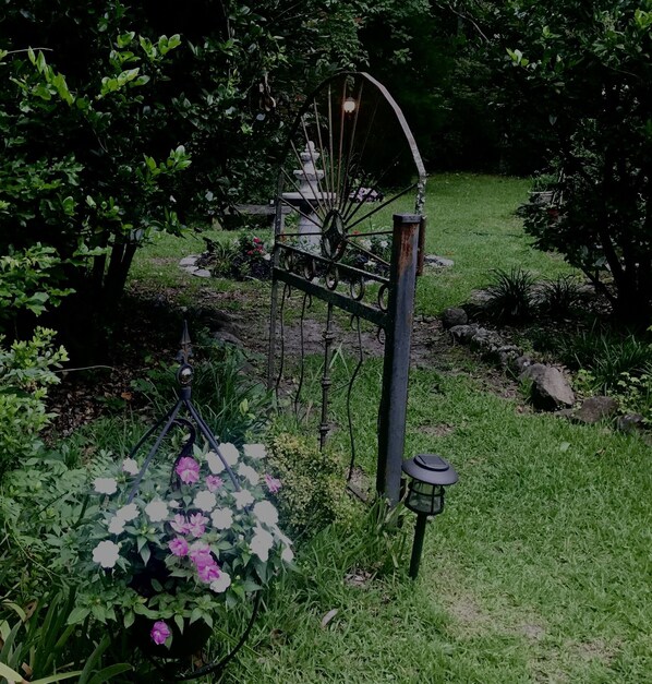 A garden with a metal sculpture, a hanging flower pot, and a lantern post. - Carriage House Villa and gardens in downtown historic Lexington SC (Lexington)