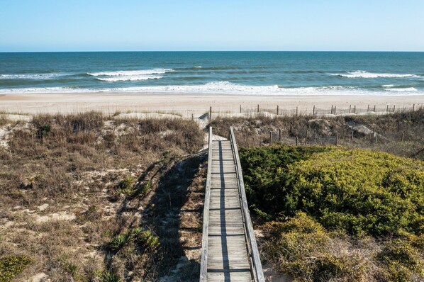 A wooden boardwalk leading to a beach with ocean views. - Spacious 3rd-Row Beach Home with Private Saltwater Pool (Emerald Isle)
