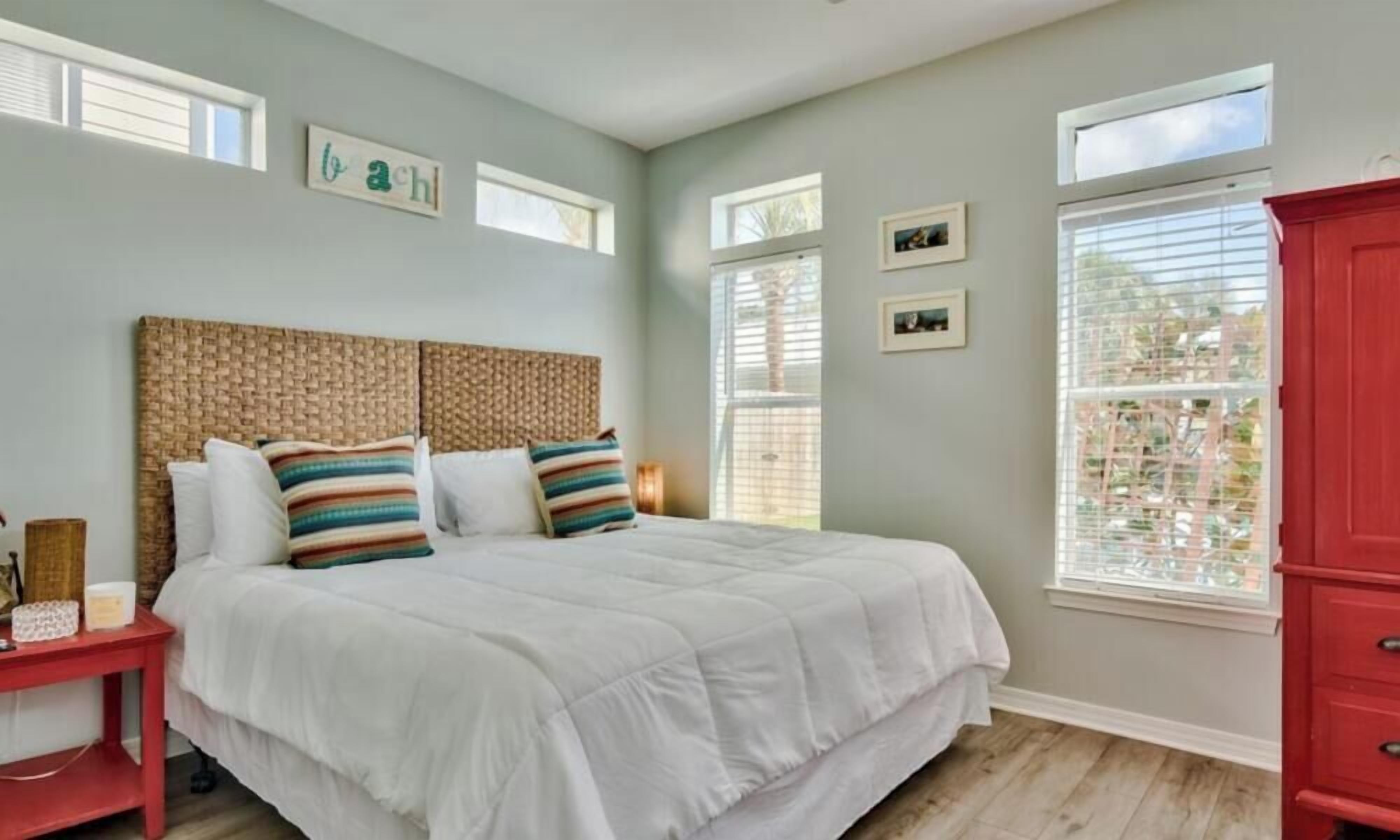 A bedroom with a bed, a nightstand, a red cabinet, and a ceiling fan.