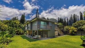 Une maison à deux étages dotée d’un patio couvert, d’un escalier et d’une pelouse bien entretenue.