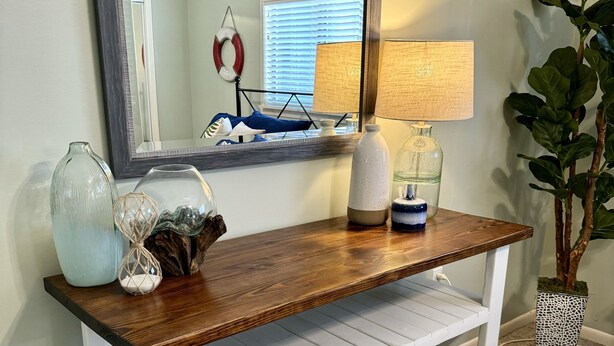 A wooden console table with a mirror above it, a lamp, and decorative items. - Cocktail Cove 4 bedroom 2 bath by Jamestown Marina (Jamestown)