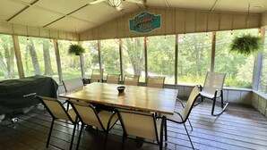 A covered outdoor dining area with a table and chairs, a ceiling fan, and a sign that reads "Welcome to Cockpit Cove." - Cocktail Cove 4 bedroom 2 bath by Jamestown Marina (Jamestown)