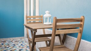 A wooden table and chairs with a white lantern on a tiled floor against a blue wall.