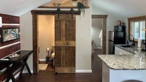 Une cuisine avec une porte en bois, des plans de travail en granit et un four à micro-ondes.