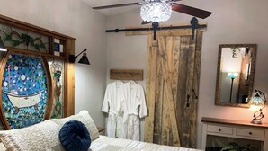 Une chambre à coucher avec un lit, une armoire en bois, un miroir et une lampe fixée au mur.