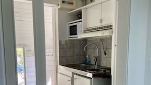 A compact kitchen with white cabinets, a microwave, and a sink. - Small cottage close to Stockholm City  (Saltsjö-boo)