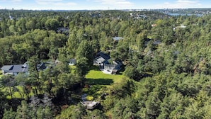 A large house surrounded by dense forest, with a well-maintained lawn and multiple buildings in the background. - Small cottage close to Stockholm City  (Saltsjö-boo)