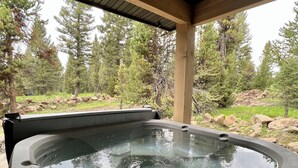 Ein Whirlpool mit einer Holterrasse und Blick auf ein bewaldetes Gebiet.