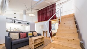 A modern living space with a staircase, a sofa set, and a kitchen area. - GuestReady - Mezzanine at the Bridge (Porto)