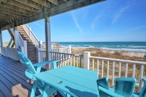 A wooden deck with a table and chairs, overlooking a beach and ocean. - Oceanfront getaway, Sea Grace: 4 Bedroom home in North Topsail Beach for 10 guests. (North Topsail Beach)