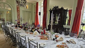 A formal dining room with a long table set for a meal, surrounded by chairs. - Château with Spa, Golf, Tennis, Basket, swimming pools, gardens.  (Villers-Bocage)