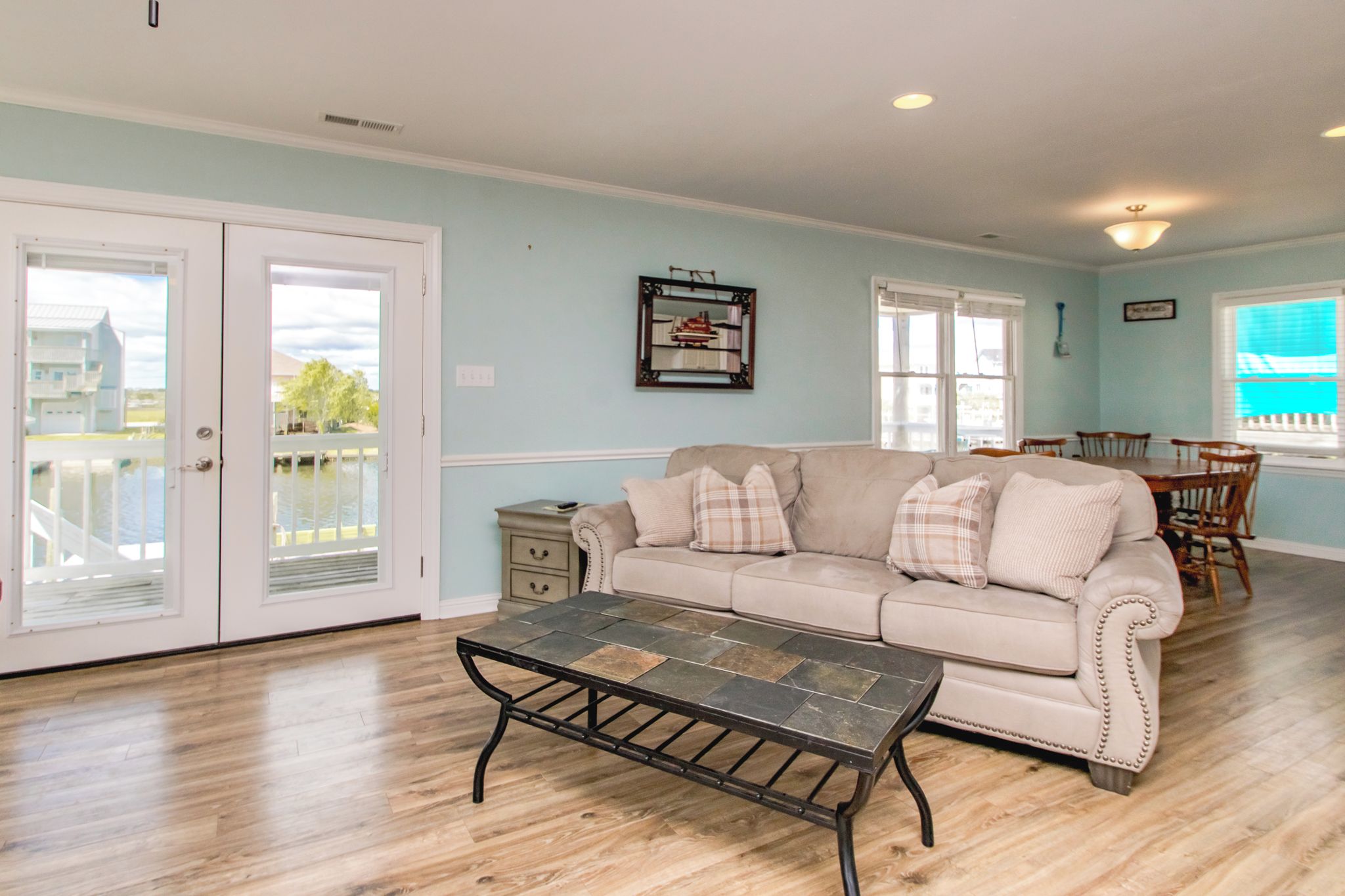 A living room with a beige sofa, a coffee table, and a dining area with wooden chairs and a table.