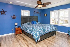 A bedroom with a bed, a nightstand, a wooden floor, a ceiling fan, and a window with a view. - Mama's Pride - 3BR Home on the Canal - Boat Dock & Sound Views! (Surf City)