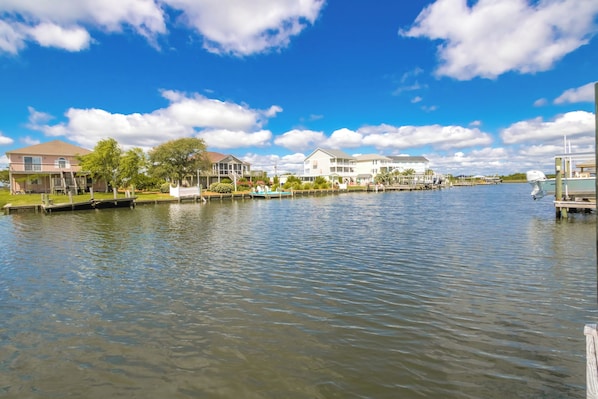 A waterfront property with a dock, a boat, and a row of houses.