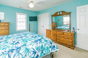 A bedroom with a bed, dresser, and a ceiling fan.