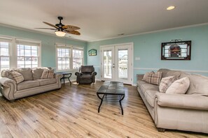 A spacious living room with two sofas, a coffee table, and a ceiling fan.