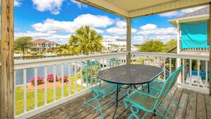 A covered outdoor area with a table and chairs, overlooking a body of water and a residential area.