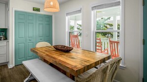 A dining area with a wooden table, wicker chairs, and a hanging light fixture. - Dream Weaver: Spacious 4BR home in Holden Beach, perfect for family getaways! (Holden Beach)